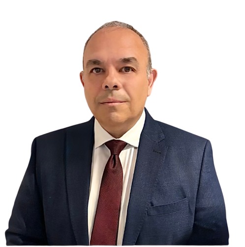 A middle-aged man wearing a dark blue suit, white shirt, and maroon tie, standing against a plain white background.